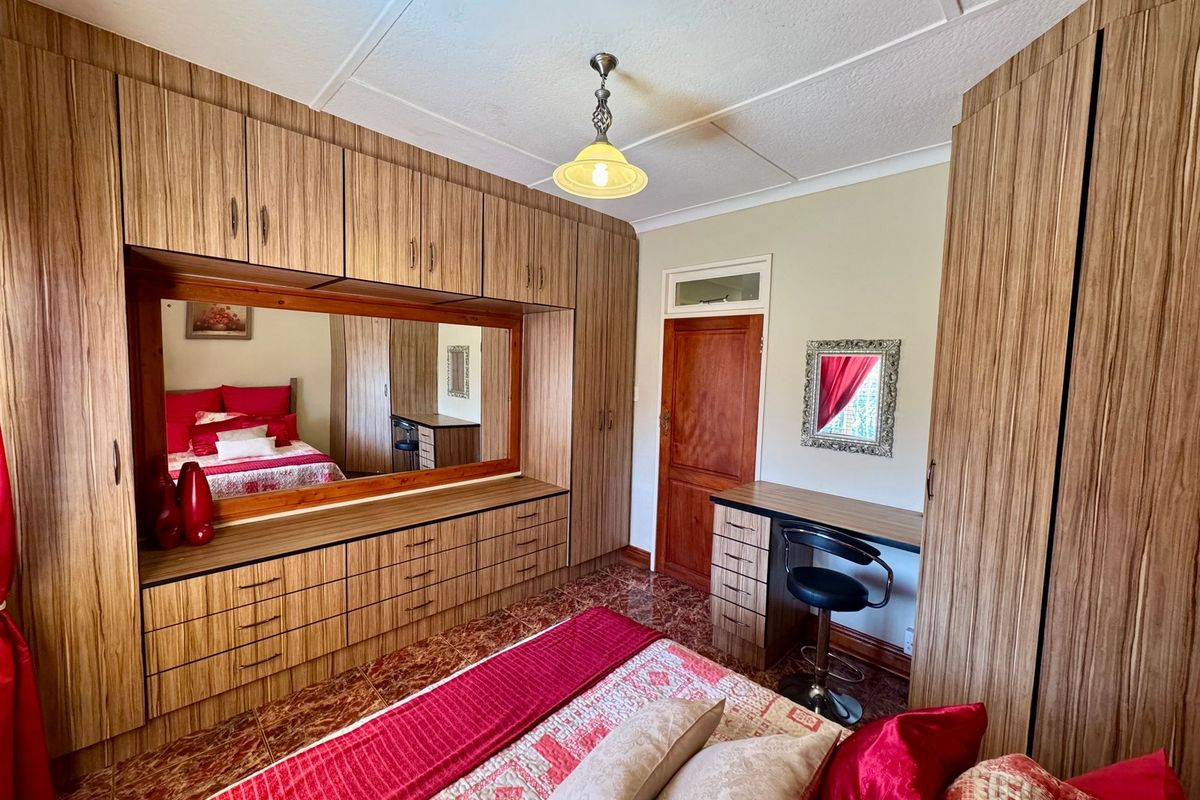 A bedroom featuring extensive built-in timber cabinetry, a integrated vanity unit, tiled flooring, and a classic timber door.