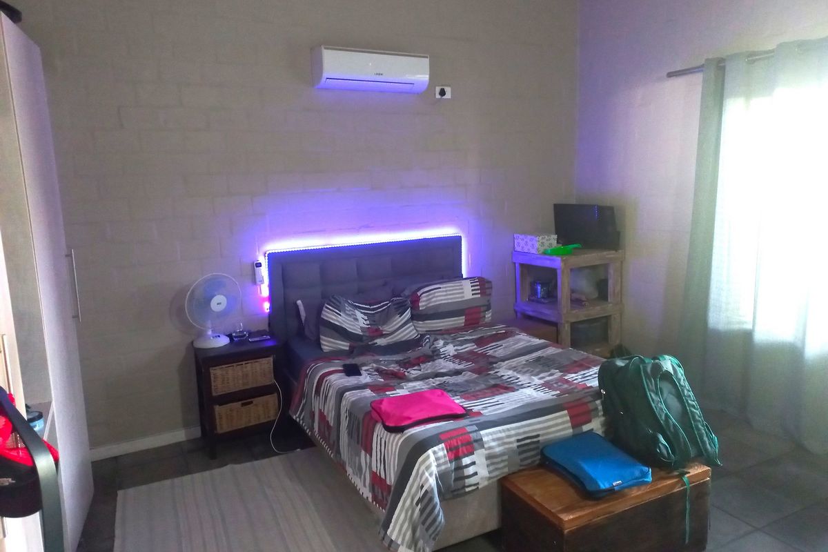 A bedroom featuring tiled flooring and a wall-mounted split-system air conditioner unit.