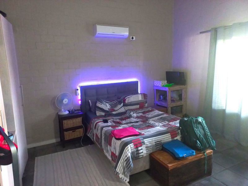 A bedroom featuring tiled flooring and a wall-mounted split-system air conditioner unit.