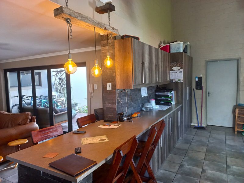 Open plan living area featuring a stone-clad breakfast bar, modern laminate cabinetry, and direct access to an outdoor patio through sliding glass doors.
