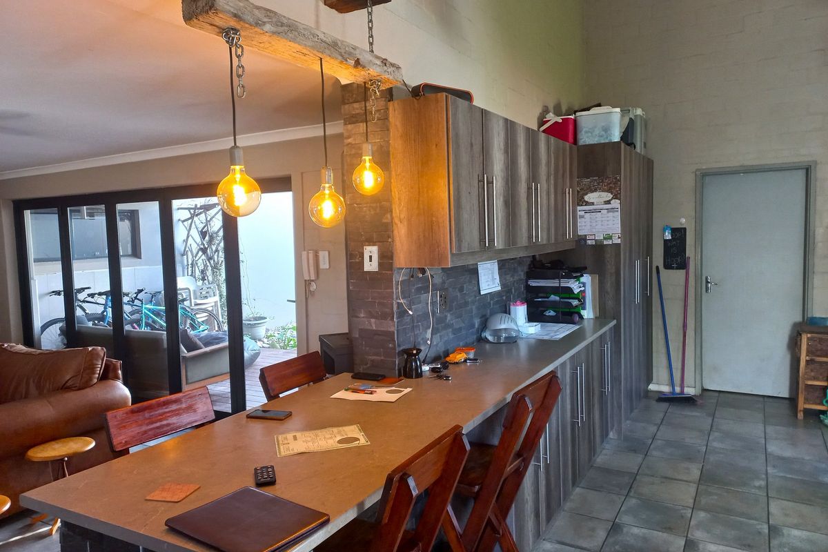 Open plan living area featuring a stone-clad breakfast bar, modern laminate cabinetry, and direct access to an outdoor patio through sliding glass doors.