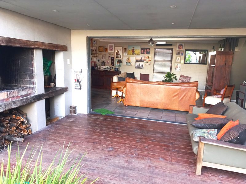 Covered patio area featuring timber decking and a built-in braai, seamlessly connecting to the indoor living space through large sliding doors.