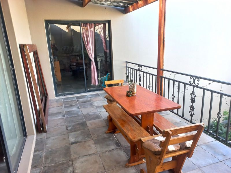 Covered patio area featuring tiled flooring, a wrought iron balustrade, and a timber pergola structure, providing an outdoor entertainment space.