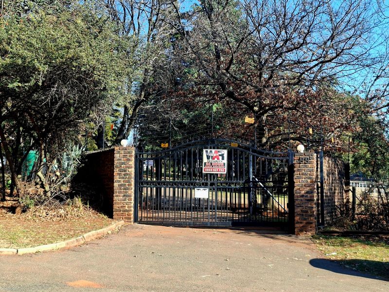 Secure gated entrance to the property featuring a brick boundary wall, wrought iron gate, and integrated electric fencing.