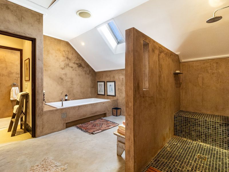 Spacious bathroom featuring a built-in bathtub, a walk-in shower with mosaic tiling, and a skylight, finished with textured plaster walls.
