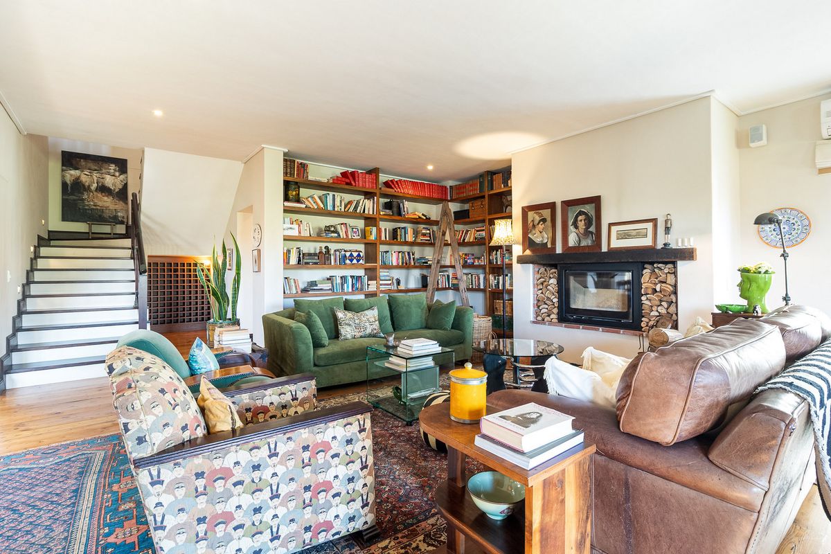 Spacious living room featuring a built-in fireplace, extensive custom bookshelves, and a staircase leading to the upper level.