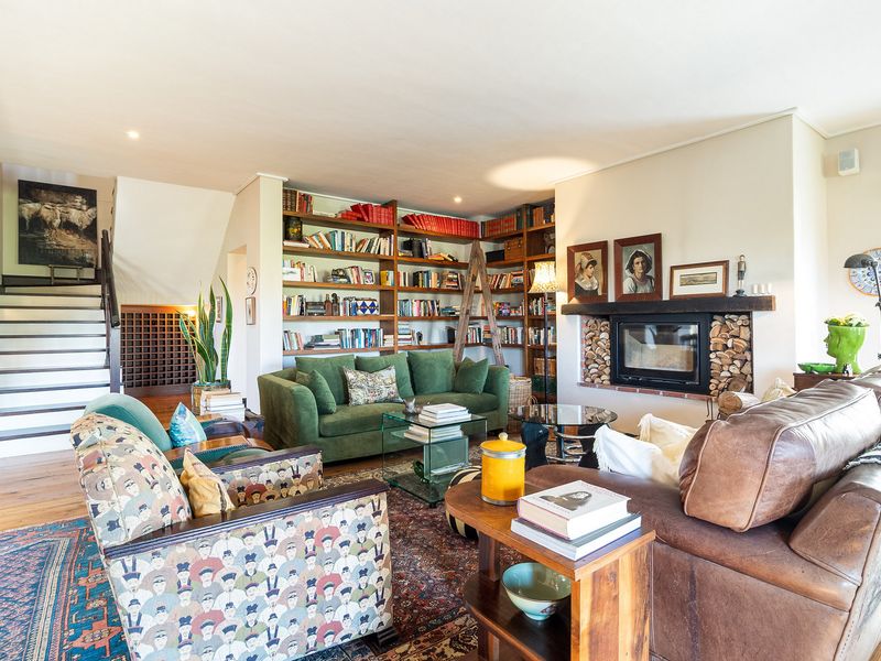 Spacious living room featuring a built-in fireplace, extensive custom bookshelves, and a staircase leading to the upper level.