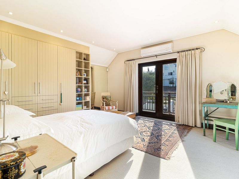Spacious bedroom featuring extensive built-in cabinetry, integrated shelving, recessed lighting, and direct access to a private balcony through double doors.