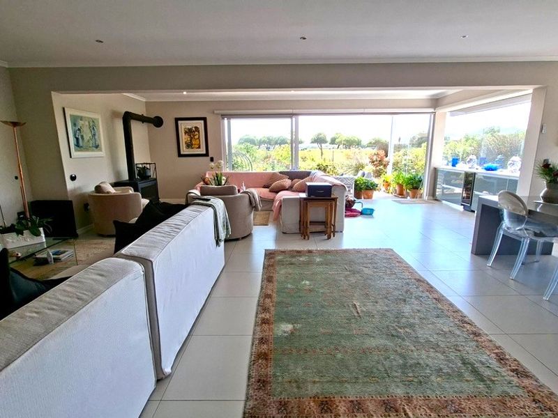 Spacious open-plan living and dining area featuring tiled floors, a modern fireplace, and large sliding doors that open to a scenic outdoor view.
