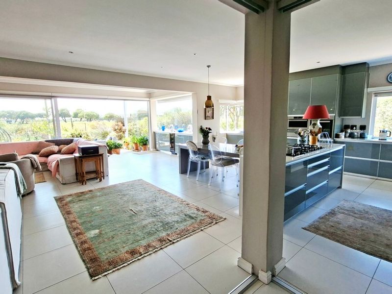Spacious open-plan living area featuring a modern kitchen with a central island, sleek cabinetry, and large sliding doors opening to the garden.