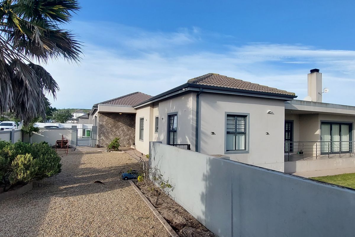 Rear view of the property featuring a paved patio, gravel garden area, and secure boundary walls.
