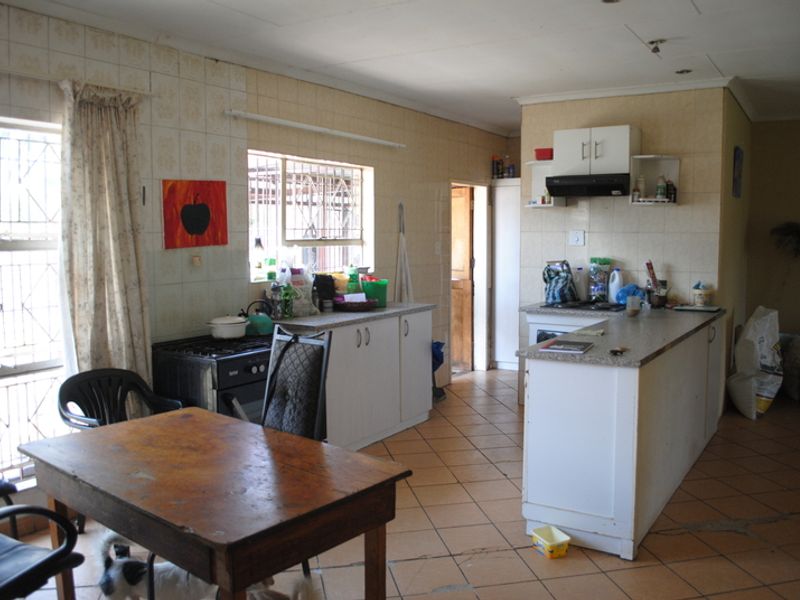 A functional kitchen featuring built-in cabinetry, a tiled splashback, and an extractor fan, offering potential for modernization and cosmetic updates.