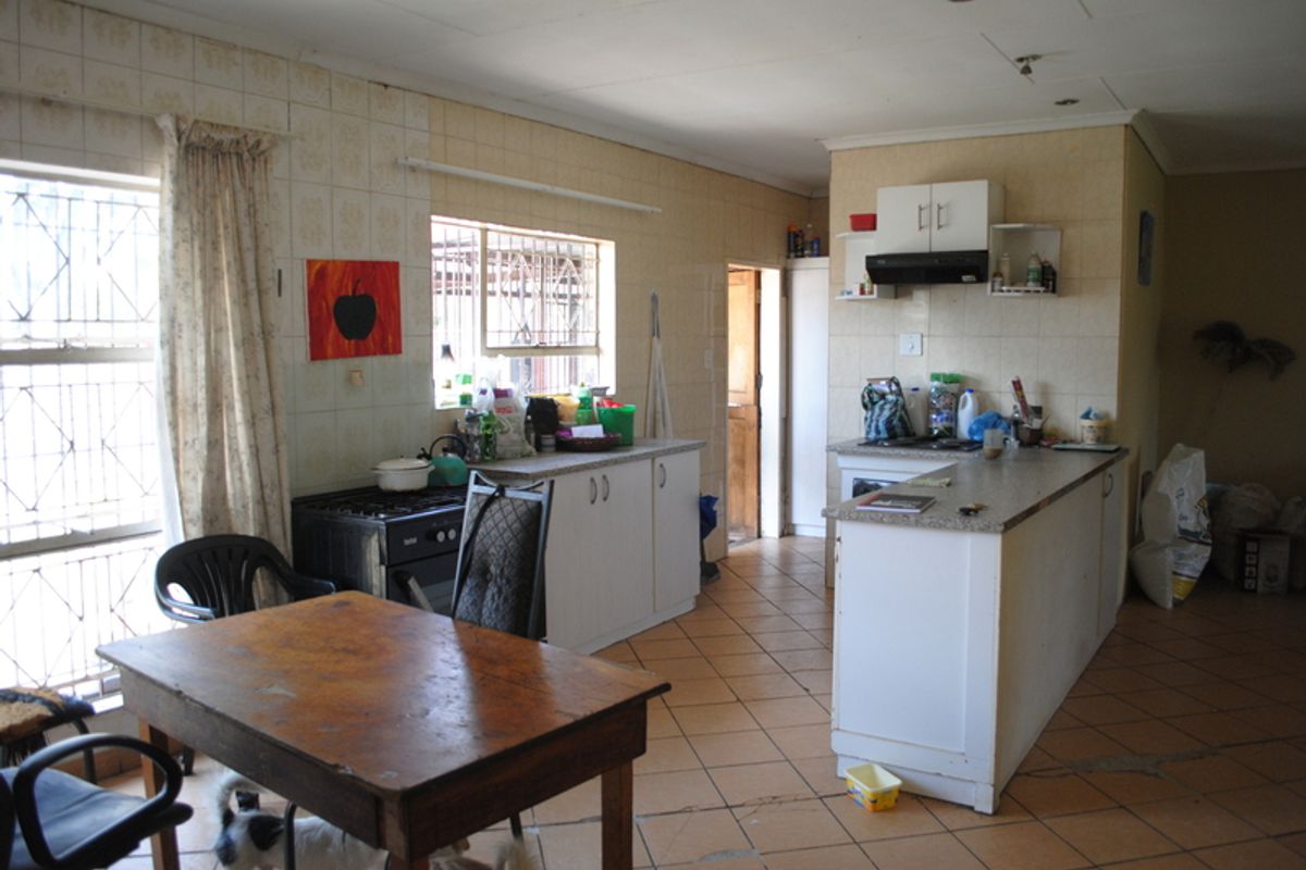 A functional kitchen featuring built-in cabinetry, a tiled splashback, and an extractor fan, offering potential for modernization and cosmetic updates.