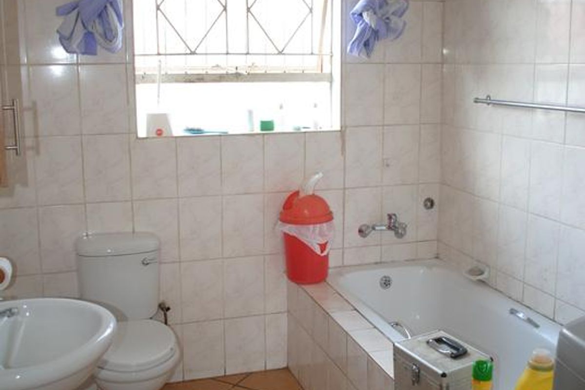 A functional bathroom featuring a pedestal basin, toilet, and built-in bathtub with tiled finishes throughout.