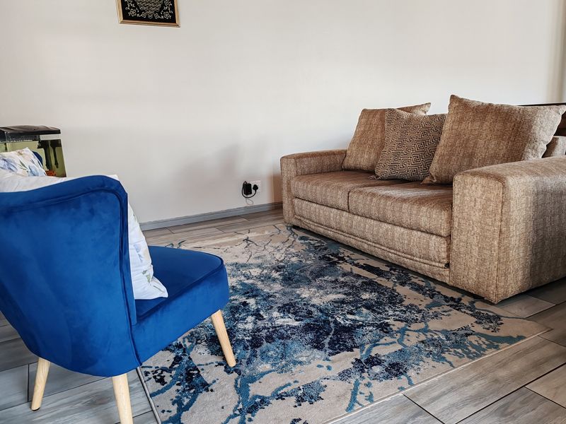 A comfortable living room area featuring neutral wall tones and modern tiled flooring, providing a clean and functional space for relaxation.