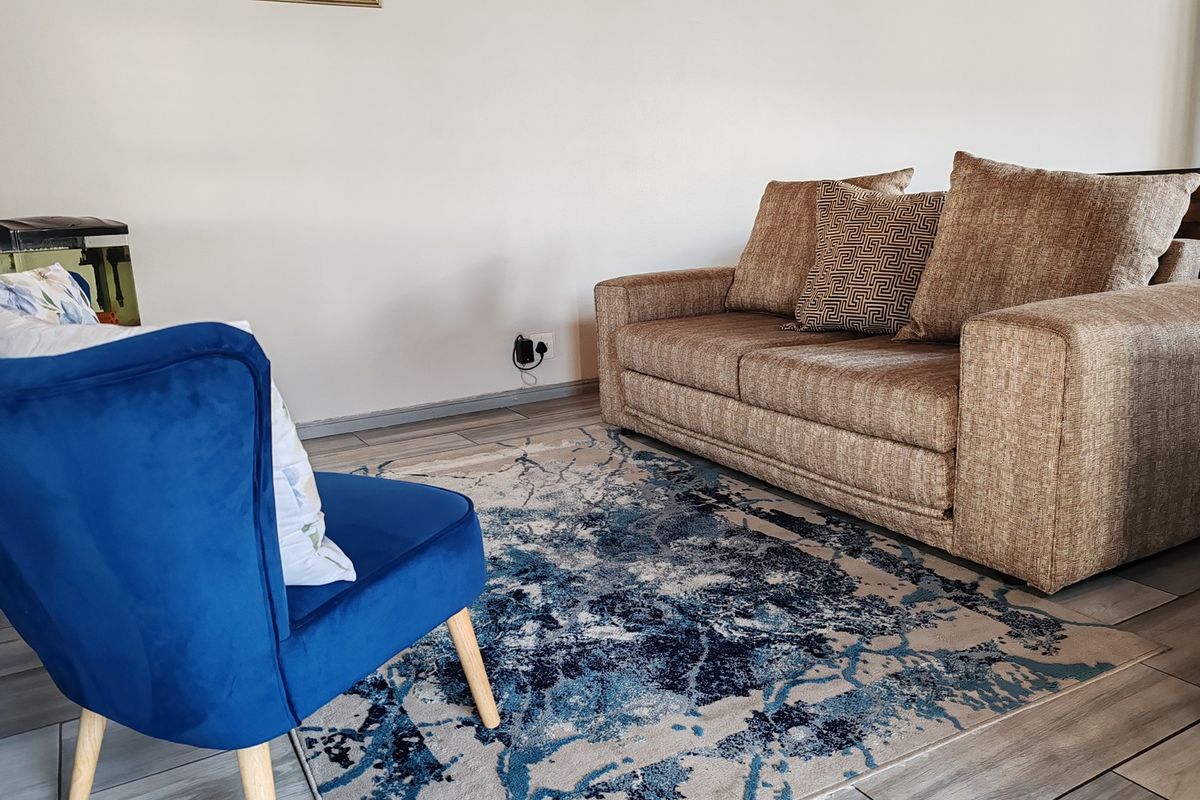 A comfortable living room area featuring neutral wall tones and modern tiled flooring, providing a clean and functional space for relaxation.