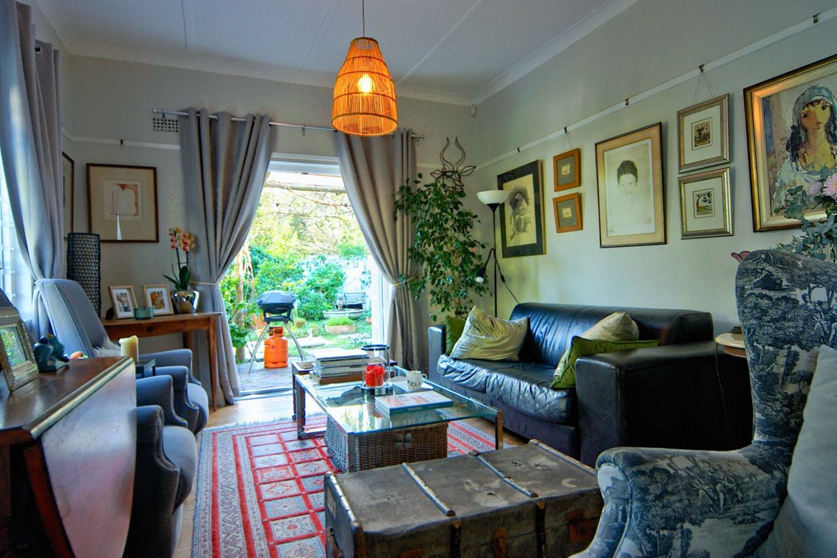 A cozy living room featuring a glass sliding door that opens to a rear garden, complemented by classic coving and picture rail detailing.