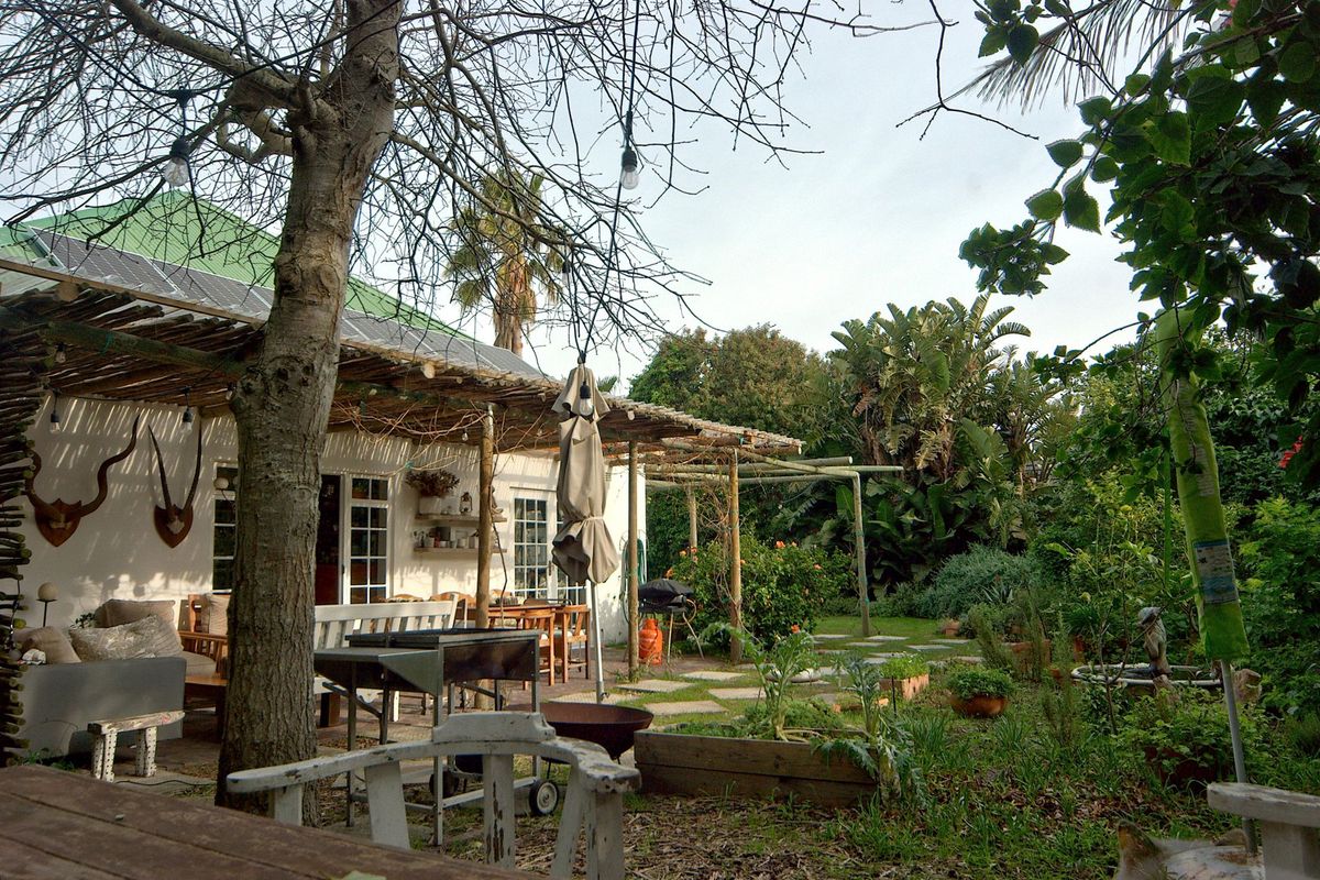 A spacious rear garden featuring a timber pergola, paved patio area, and established landscaping with solar panels installed on the main house roof.