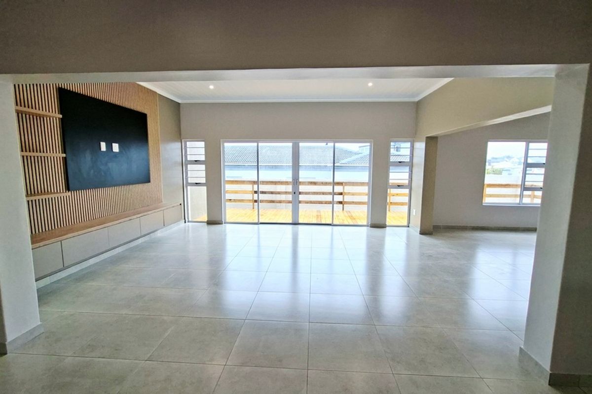 Spacious, light-filled living area featuring modern tiled floors, a contemporary slatted timber feature wall with built-in cabinetry, and large sliding doors leading to a balcony.