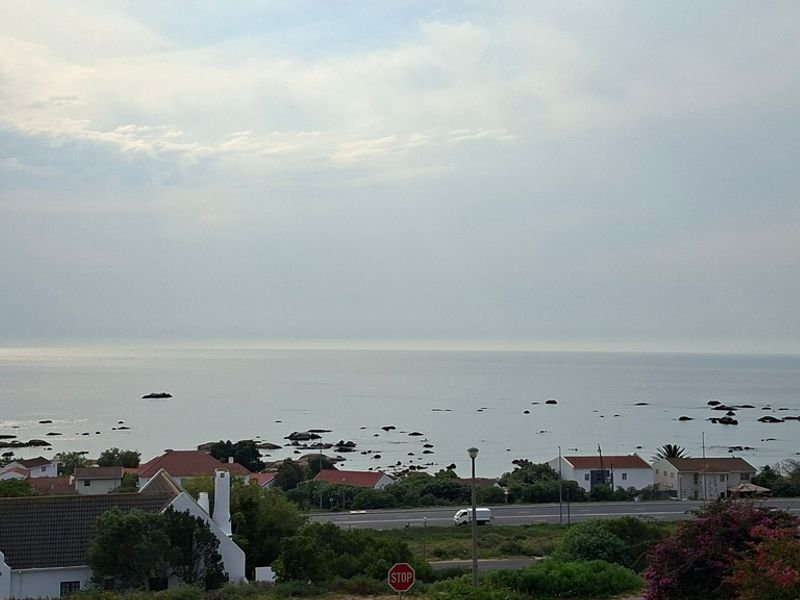 A scenic elevated view overlooking the coastline, nearby residential properties, and the ocean horizon.