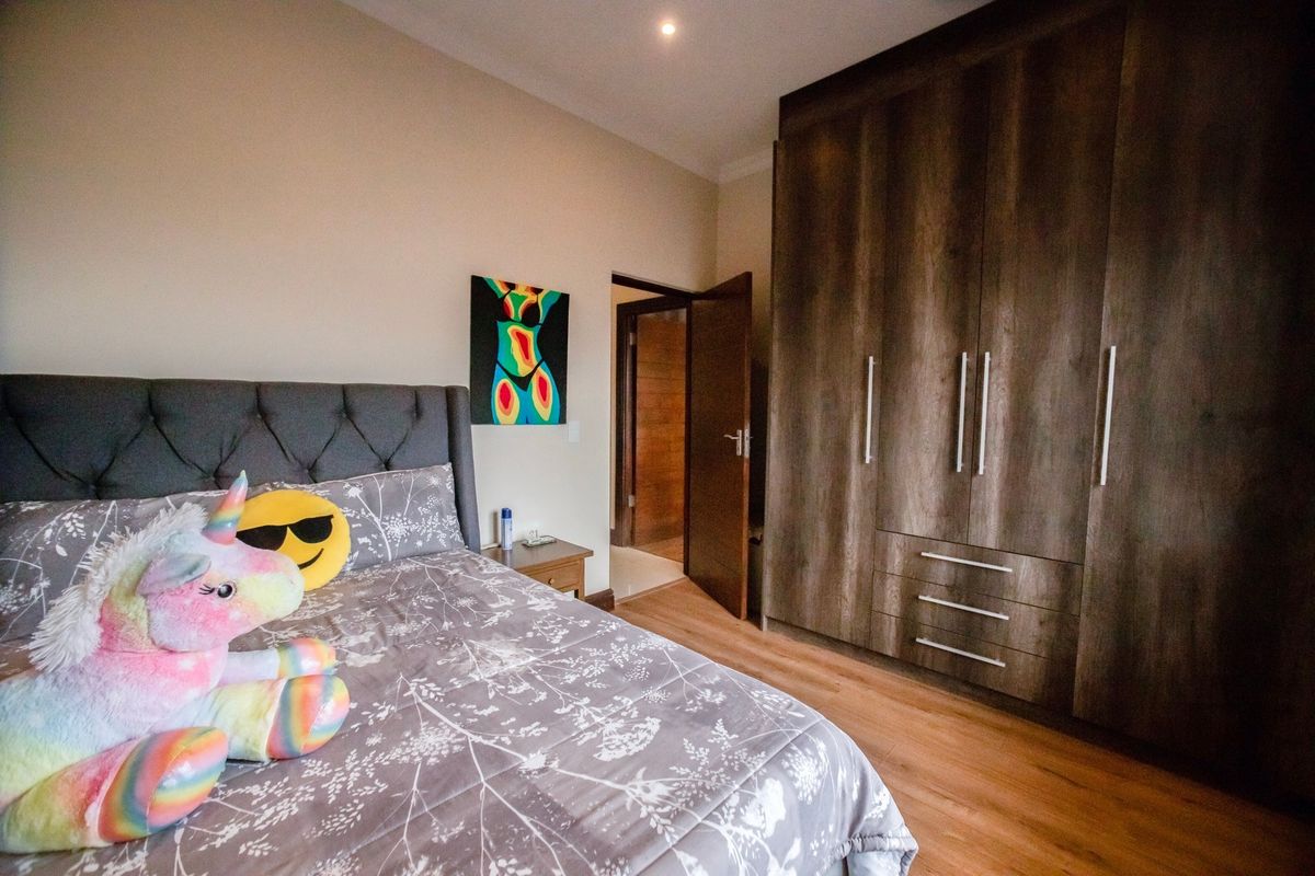 A well-maintained bedroom featuring dark wood built-in cupboards, laminate flooring, and recessed lighting, offering a clean and functional living space.