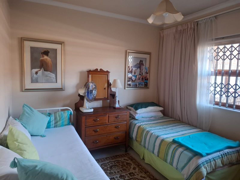 A functional bedroom featuring a window with a security gate and neutral wall finishes.