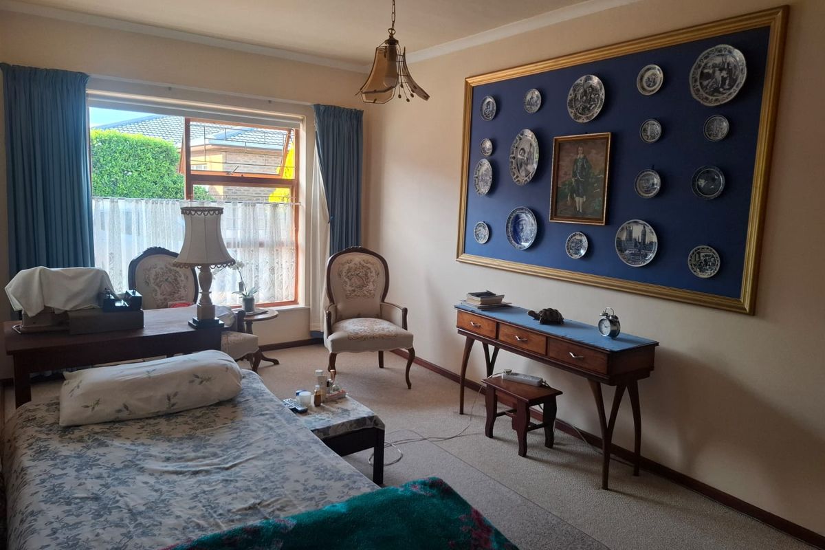A well-lit bedroom featuring carpeted flooring, a large window providing natural light, and classic coving detail.