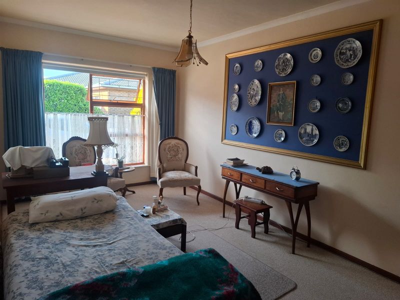 A well-lit bedroom featuring carpeted flooring, a large window providing natural light, and classic coving detail.