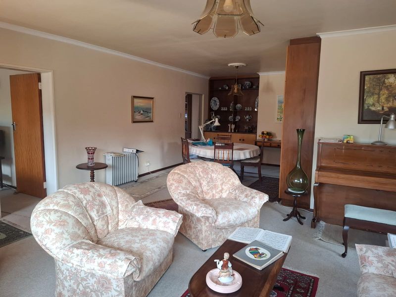 Spacious open-plan living and dining area featuring neutral walls, carpeted flooring, and built-in display cabinetry, offering a versatile layout for comfortable living.