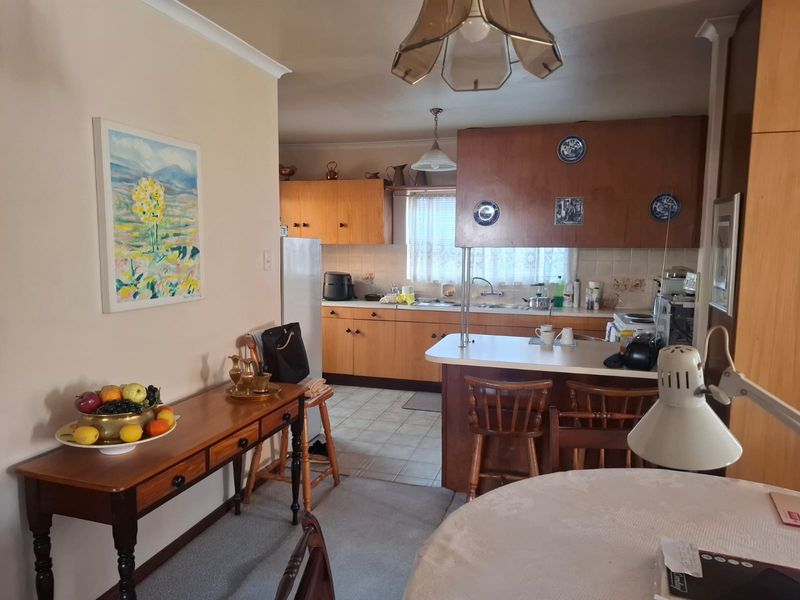 Open plan kitchen and dining area featuring traditional wooden cabinetry, a breakfast bar, and tiled flooring, offering a functional layout with potential for modernization.