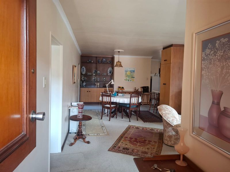 Open plan living and dining area featuring neutral wall finishes, carpet flooring, and built-in cabinetry, providing a functional and versatile living space.