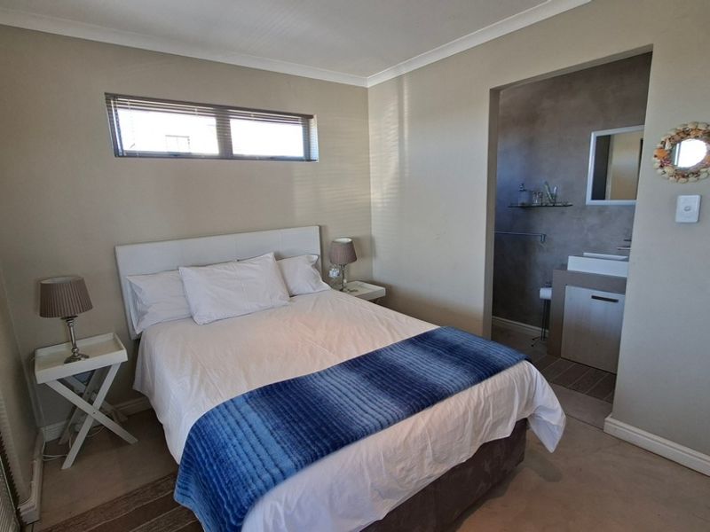 A well-lit bedroom featuring a horizontal window, neutral wall finishes, and an adjoining en-suite bathroom with modern vanity.