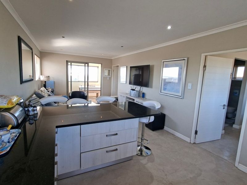 Open plan living area featuring a modern kitchen island with granite countertops, recessed lighting, and seamless flow to the adjacent balcony area.