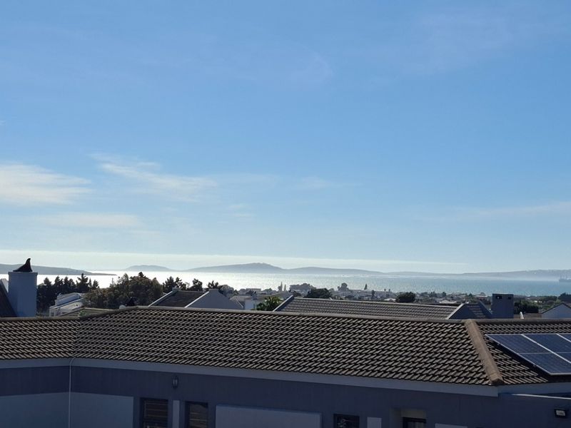 Elevated view overlooking the surrounding neighborhood rooftops with a clear outlook towards the distant coastline and ocean.