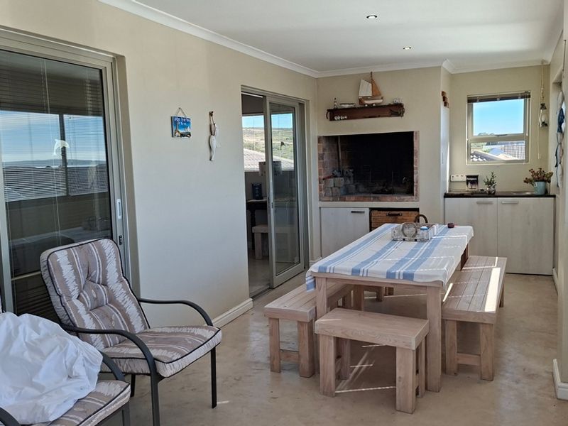 Enclosed patio area featuring a built-in braai, tiled flooring, and sliding glass doors, providing a versatile space for indoor-outdoor entertaining.