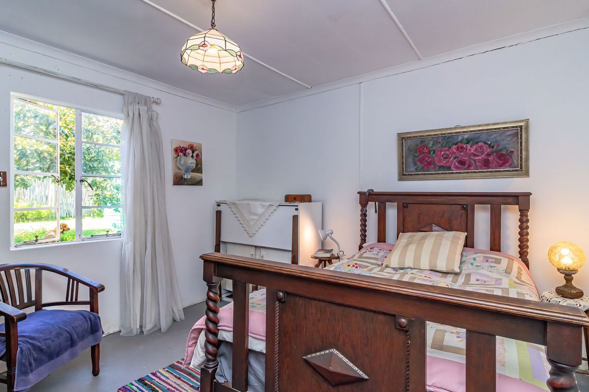 A bedroom featuring a casement window and a ceiling light fixture, with visible cracks in the ceiling panels.