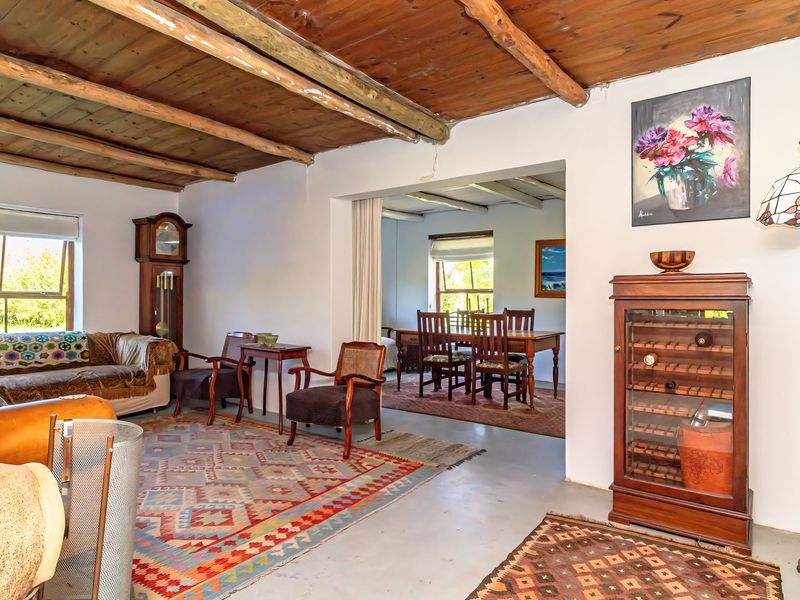 Open plan living and dining area featuring exposed timber beam ceilings, concrete flooring, and a prominent freestanding fireplace.