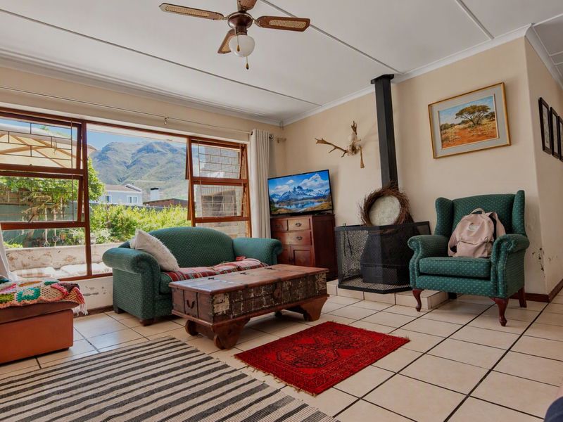 Living room featuring tiled flooring, a wood-burning fireplace, and large windows with mountain views. Requires maintenance for visible wall dampness.
