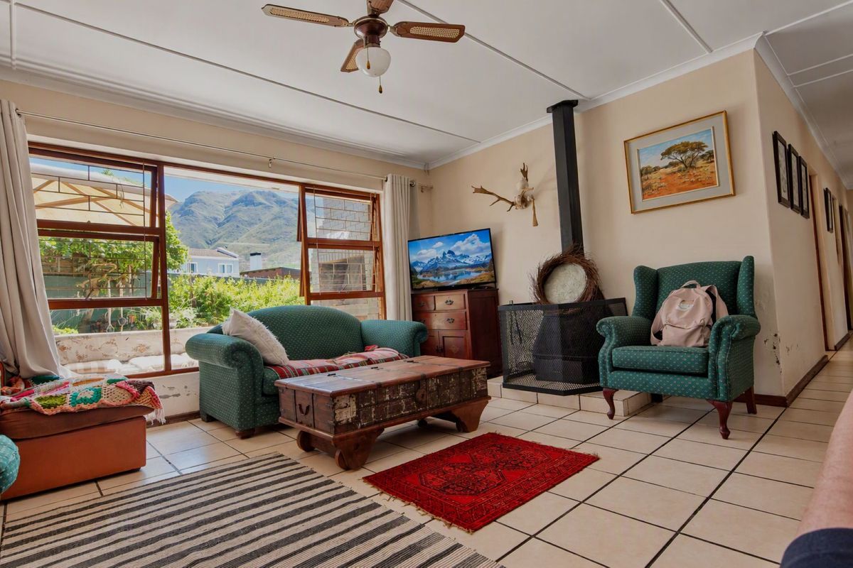 Living room featuring tiled flooring, a wood-burning fireplace, and large windows with mountain views. Requires maintenance for visible wall dampness.