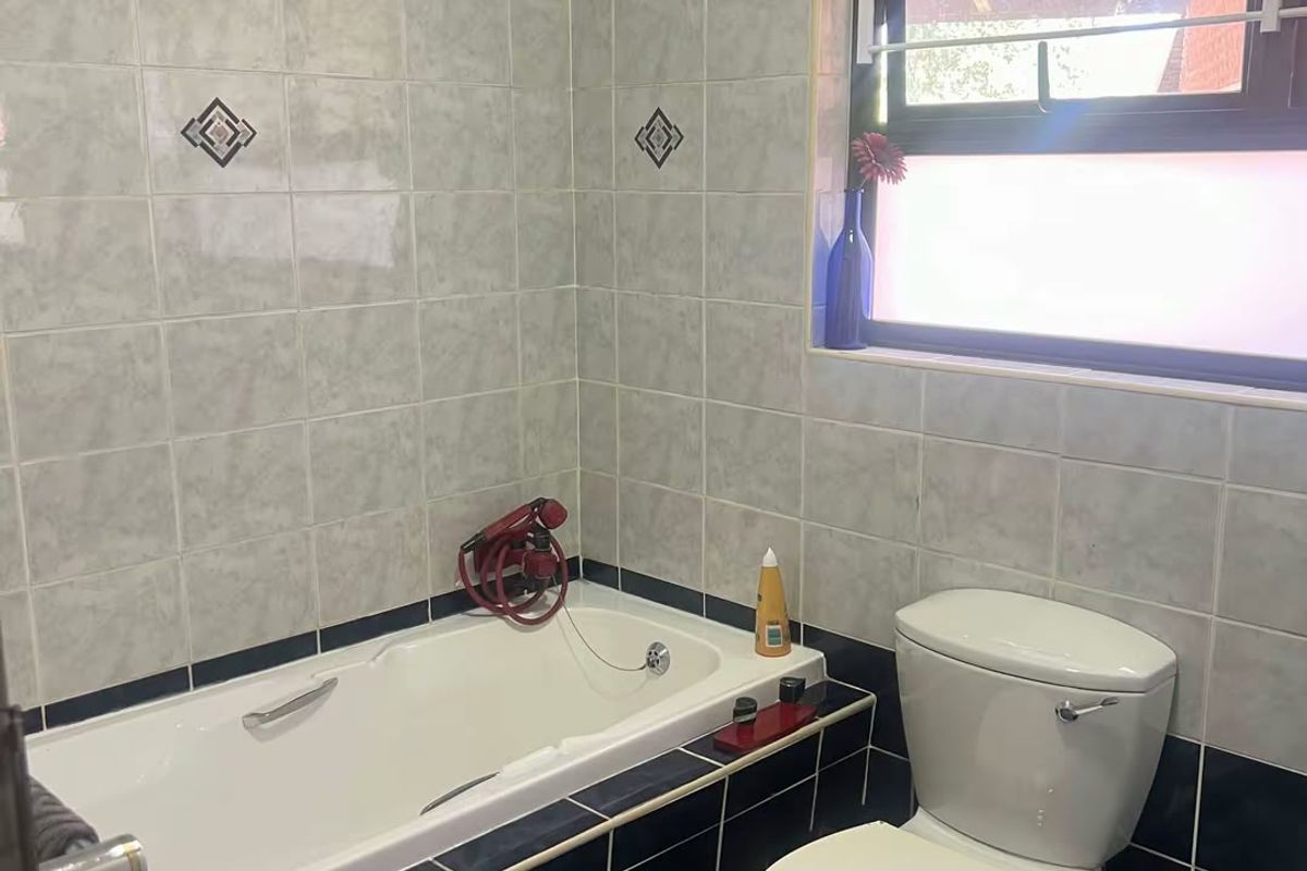 A functional bathroom featuring a built-in bathtub, toilet, and classic tiled finishes, offering a solid foundation for modern updates.