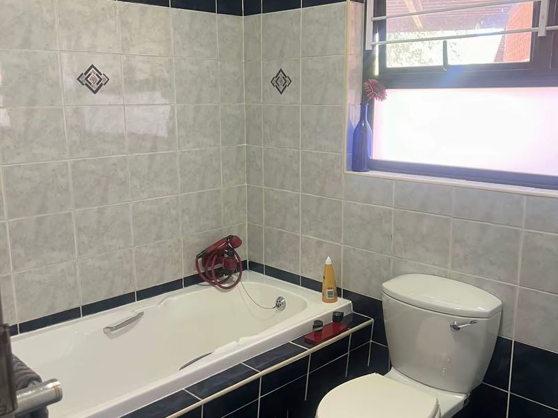A functional bathroom featuring a built-in bathtub, toilet, and classic tiled finishes, offering a solid foundation for modern updates.