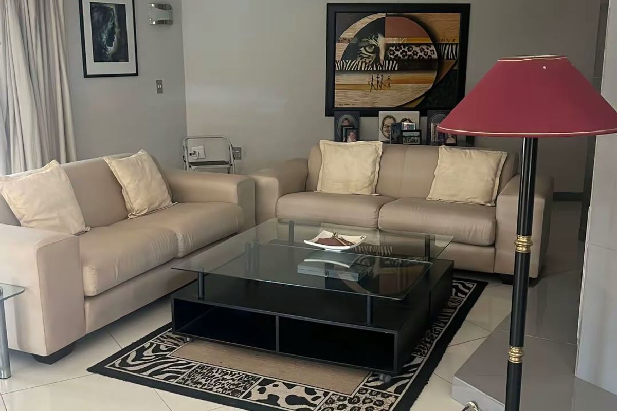 A well-maintained living room featuring neutral tiled flooring, recessed lighting, and a fireplace hearth, offering a comfortable and functional space.