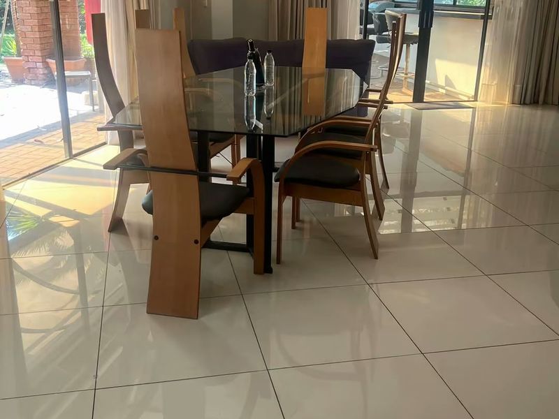 Spacious dining area featuring large format polished floor tiles and expansive sliding glass doors providing seamless access to the outdoor patio.