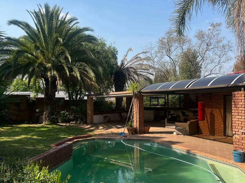 Outdoor pool area featuring a swimming pool, brick patio, and a covered entertainment space with brick pillars.