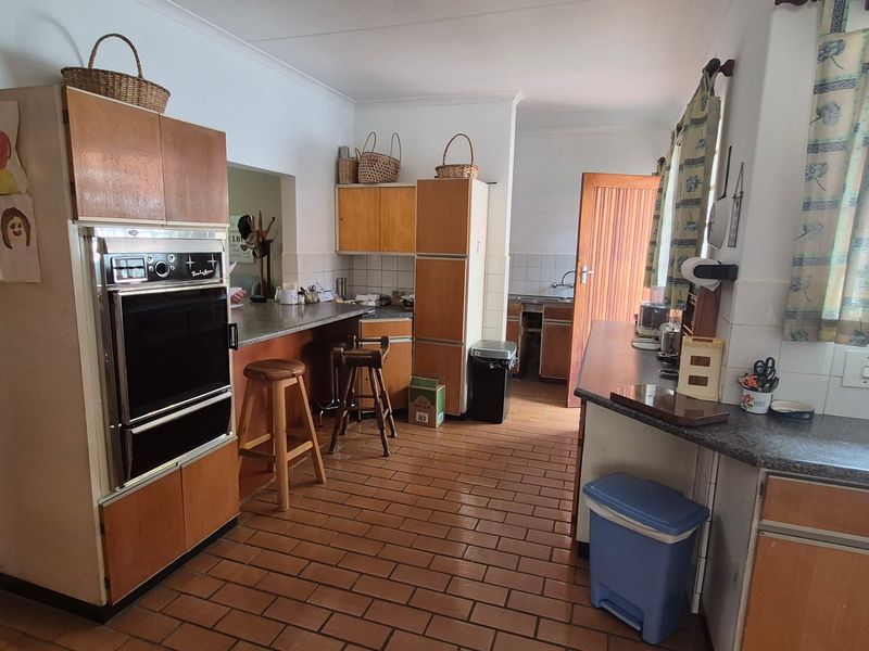 A functional kitchen featuring dated laminate cabinetry, built-in oven, tiled flooring, and a secondary prep area with a sink.