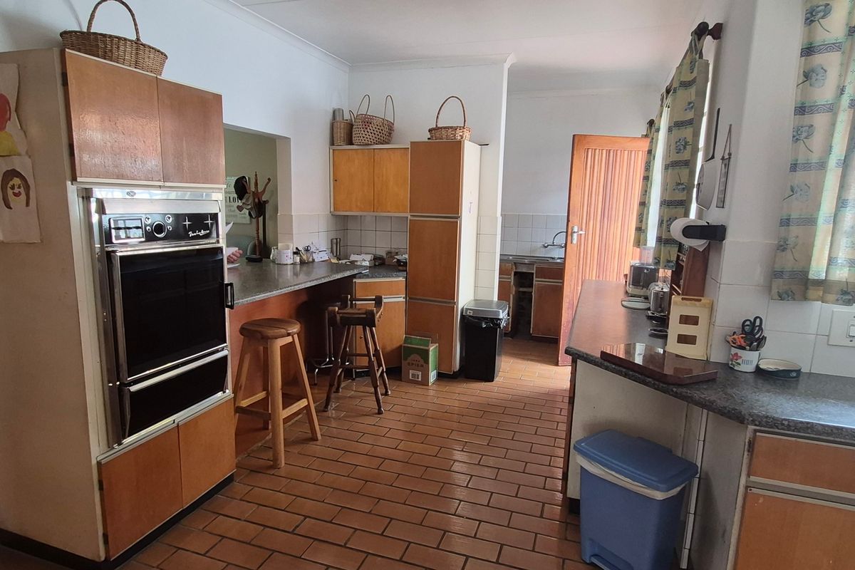 A functional kitchen featuring dated laminate cabinetry, built-in oven, tiled flooring, and a secondary prep area with a sink.