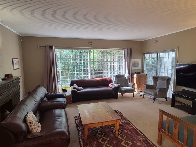 Spacious living room featuring a brick fireplace, large grid-style windows, and sliding glass doors that provide ample natural light.