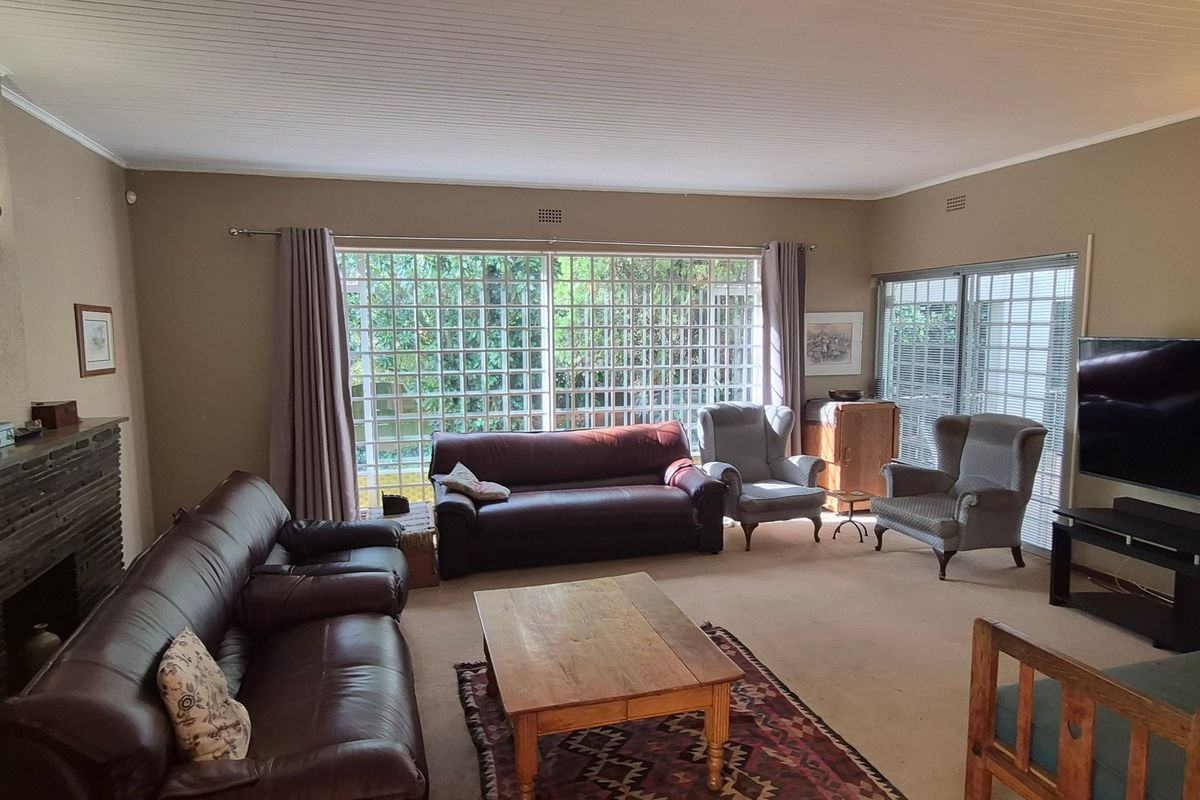 Spacious living room featuring a brick fireplace, large grid-style windows, and sliding glass doors that provide ample natural light.