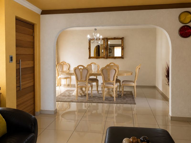 A well-lit dining area featuring polished tile flooring and a distinctive arched entryway, connecting seamlessly to the adjacent living space.
