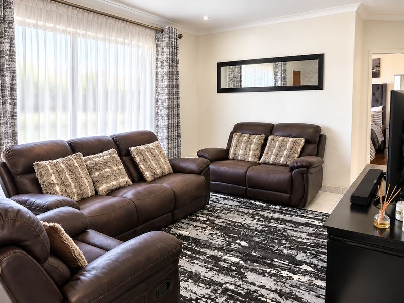A well-maintained living room featuring tiled flooring, recessed downlighting, and a large window that allows for ample natural light.